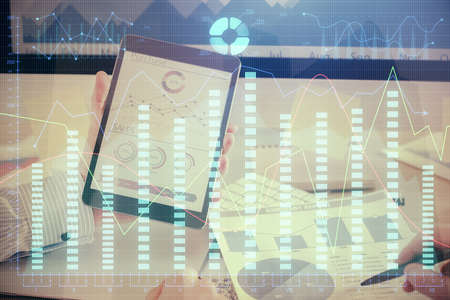 Double exposure of man's hands holding and using a digital device and forex graph drawing. Financial...