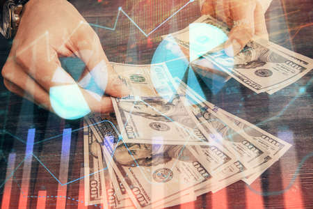 Multi exposure of financial graph drawing hologram and USA dollars bills and man hands. Analysis...