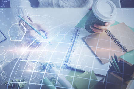 Double exposure of hands making notes with world map hologram and data theme icons. Concept of...