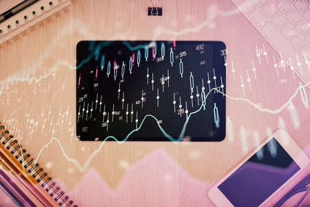 Double exposure of forex graph hologram over desktop with phone. Top view. Mobile trade platform concept.の写真素材