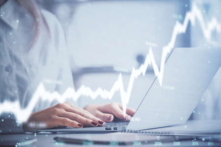 Double exposure of woman hands working on computer and forex graph hologram drawing. Financial...