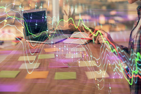 Double exposure of woman hands working on computer and forex graph hologram drawing. Financial...