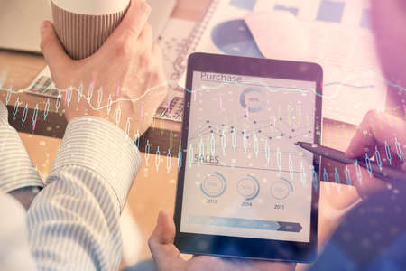 Double exposure of man's hands holding and using a phone and financial chart drawing. Market...