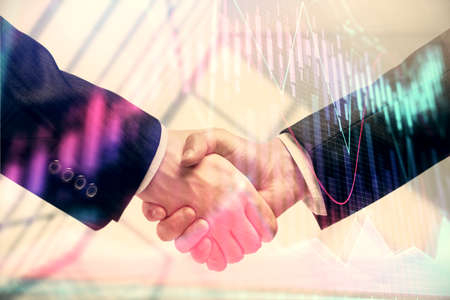 Double exposure of forex graph hologram and handshake of two men. Stock market concept.の写真素材