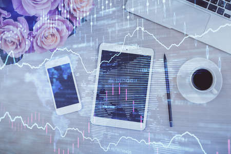 Double exposure of forex graph hologram over desktop with phone. Top view. Mobile trade platform...