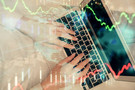 Double exposure of woman hands working on computer and forex graph hologram drawing. Top View....