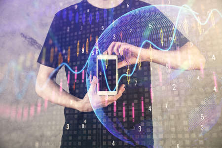 Double exposure of mans hands holding and using a digital device and forex graph drawing. Financial...