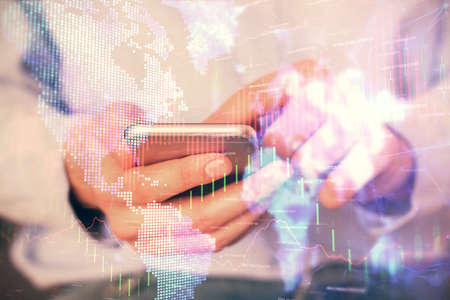 Multi exposure of mans hands holding and using a digital phone and forex graph drawing. Financial...