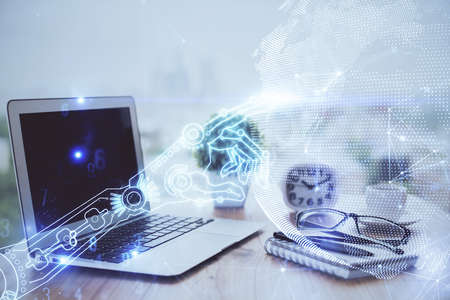 Computer on desktop in office with technology theme hologram. Double exposure. Tech concept.