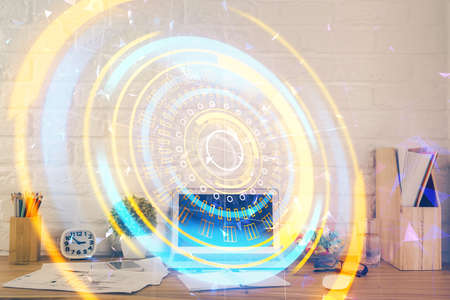 Computer on desktop in office with technology theme hologram. Double exposure. Tech concept.