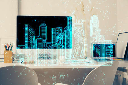 Desktop computer background in office and big town buildings hologram drawing. Double exposure....