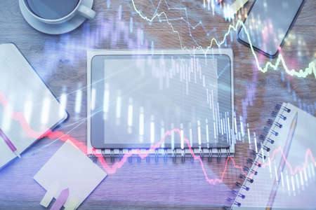 Double exposure of forex chart hologram over desktop with phone. Top view. Mobile trade platform...