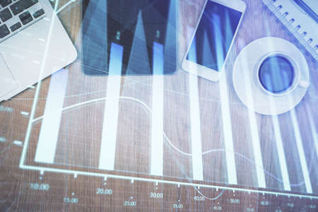 Multi exposure of forex graph hologram over desktop with phone. Top view. Mobile trade platform...