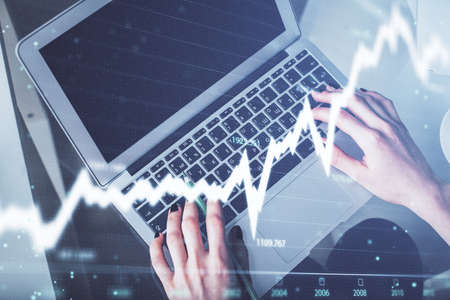 Double exposure of woman hands working on computer and forex chart hologram drawing. Top View....