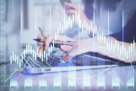 Multi exposure of woman hands typing on computer and financial graph hologram drawing. Stock market...