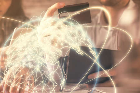 Double exposure of man and woman on-line shopping holding a credit card and business theme hologram...