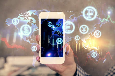 Double exposure of mans hands holding and using a digital device and forex graph drawing. Financial...