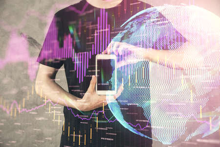Double exposure of mans hands holding and using a digital device and forex graph drawing. Financial...