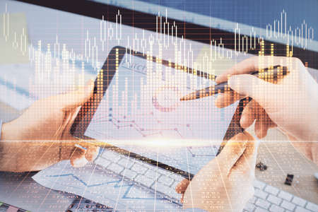 Double exposure of mans hands holding and using a phone and financial chart drawing. Market analysis...
