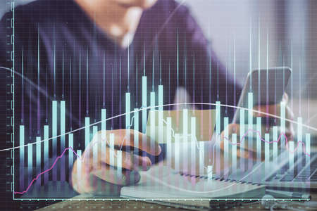 Double exposure of mans hands holding and using a phone and financial graph drawing. Analysis...