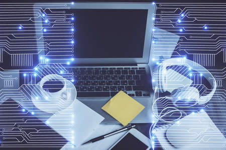 Computer on desktop in office with technology theme hologram. Double exposure. Tech concept.