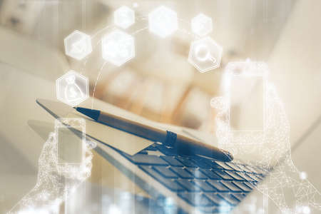 Computer on desktop in office with technology theme hologram. Double exposure. Tech concept.