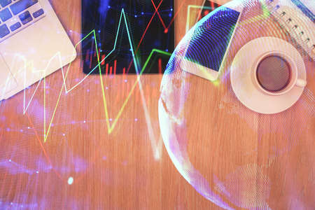 Double exposure of financial chart hologram over desktop with phone. Top view. Mobile trade platform...