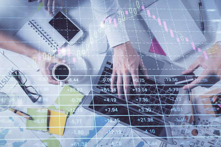 Multi exposure of mans hands typing over computer keyboard and forex graph hologram drawing. Top...