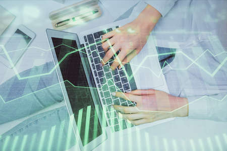 Double exposure of woman hands working on computer and forex graph hologram drawing. Top View....