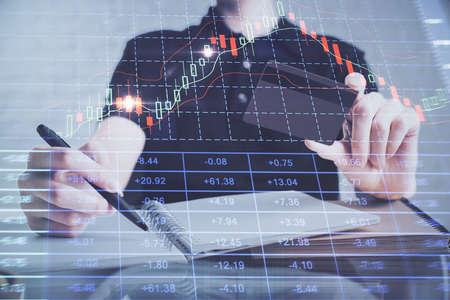 Double exposure of man hands holding a credit card and Forex graph drawing. Stock trading and...