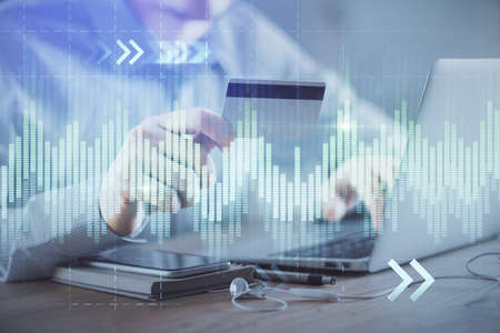 Double exposure of man hands holding a credit card and Forex graph drawing. Stock trading and...