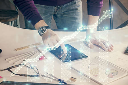 Double exposure of mans hands holding and using a digital device and forex graph drawing. Financial...
