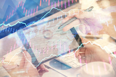 Double exposure of mans hands holding and using a phone and financial chart drawing. Market analysis...