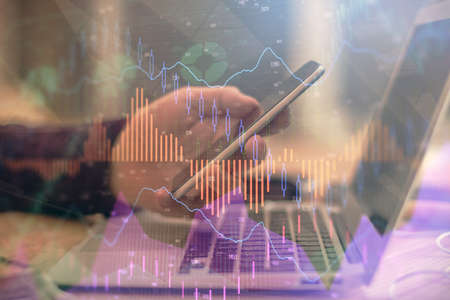 Double exposure of mans hands holding and using a phone and financial graph drawing. Analysis concept.の写真素材