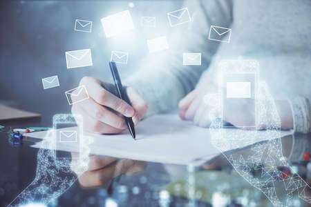 E-mail envelop theme hologram over hands taking notes background. Concept of electronic mail. Double exposureの写真素材