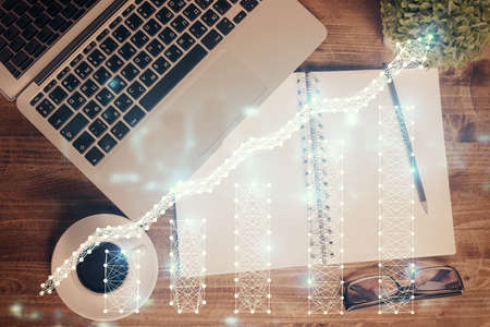 Financial market graph and top view computer on the desktop background. Double exposure. Investment...