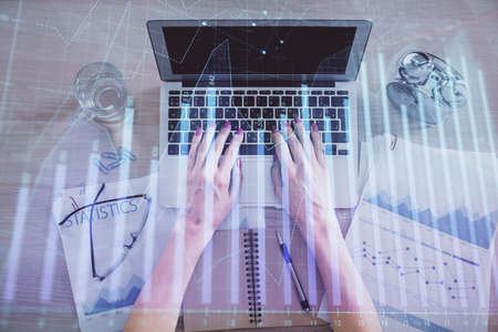 Double exposure of woman hands working on computer and forex graph hologram drawing. Top View....