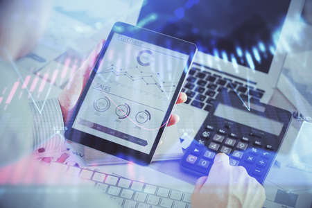 Double exposure of mans hands holding and using a digital device and forex graph drawing. Financial market concept.の写真素材