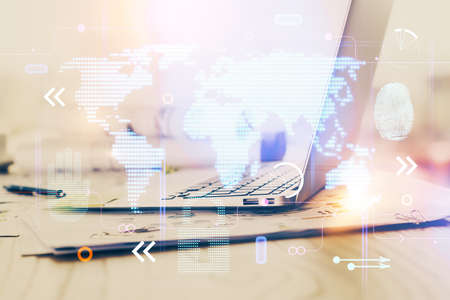 Double exposure of desktop with computer and world map hologram. International data network concept.