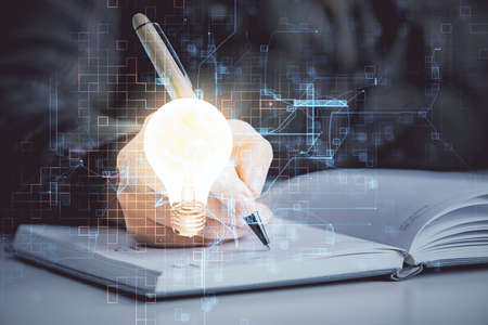 Bulb hologram over hands taking notes background. Concept of idea. Double exposureの写真素材