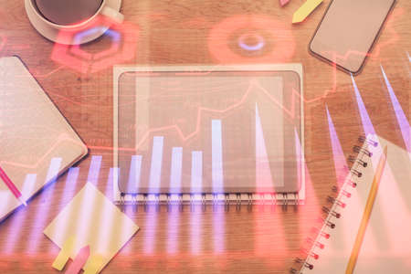 Double exposure of forex chart hologram over desktop with phone. Top view. Mobile trade platform...