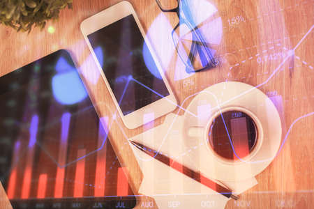 Double exposure of forex chart hologram over desktop with phone. Top view. Mobile trade platform concept.の写真素材
