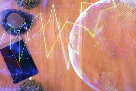 Multi exposure of financial chart hologram over desktop with phone. Top view. Mobile trade platform...