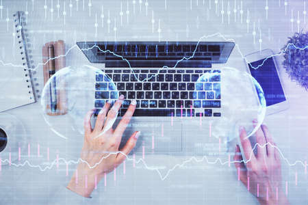 Double exposure of woman hands working on computer and forex chart hologram drawing. Top View....