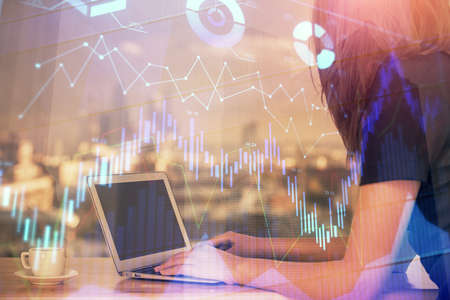 Double exposure of businesswoman hands typing on computer and forex chart hologram drawing....
