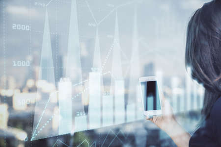 Double exposure of forex chart sketch hologram and woman holding and using a mobile device. Stock market concept.の写真素材