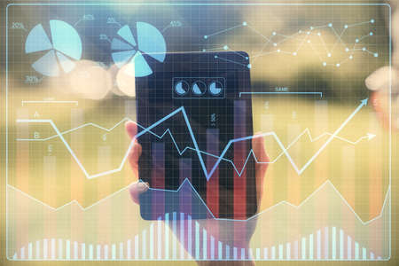 Double exposure of forex chart sketch hologram and woman holding and using a mobile device. Financial market concept.の写真素材