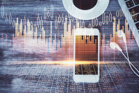 Double exposure of forex chart hologram over desktop with phone. Top view. Mobile trade platform...