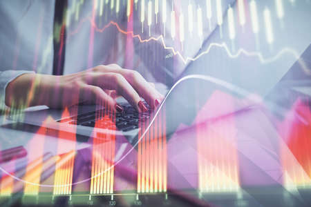 Double exposure of woman hands typing on computer and financial graph hologram drawing. Stock market...