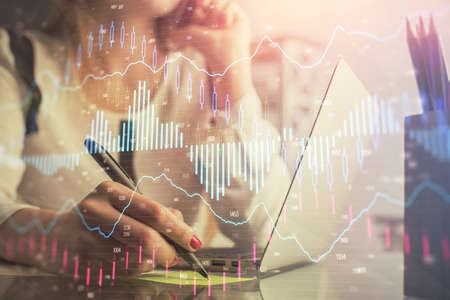 Double exposure of woman hands typing on computer and financial graph hologram drawing. Stock market...